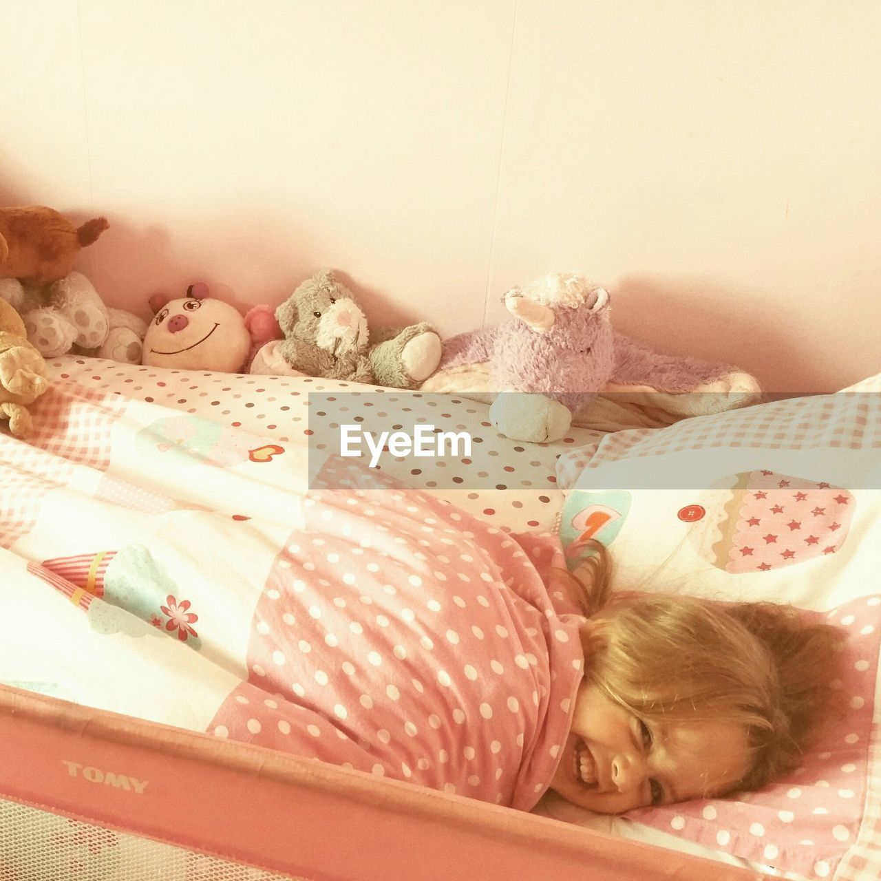 High angle view of cheerful girl lying on bed