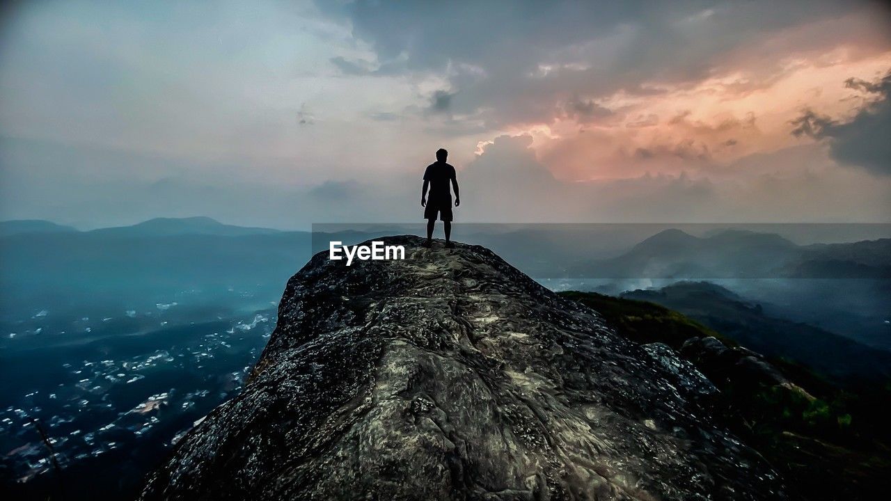 rear view of man walking on mountain against sky