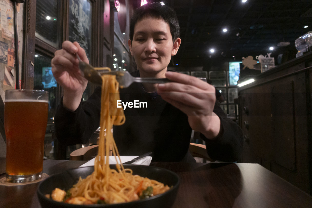 PORTRAIT OF YOUNG MAN EATING FOOD AT RESTAURANT