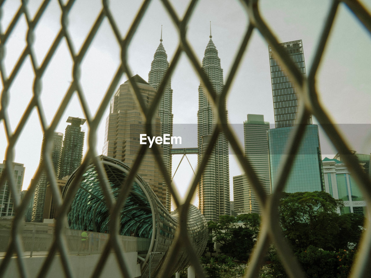Panoramic shot of buildings seen through chainlink fence