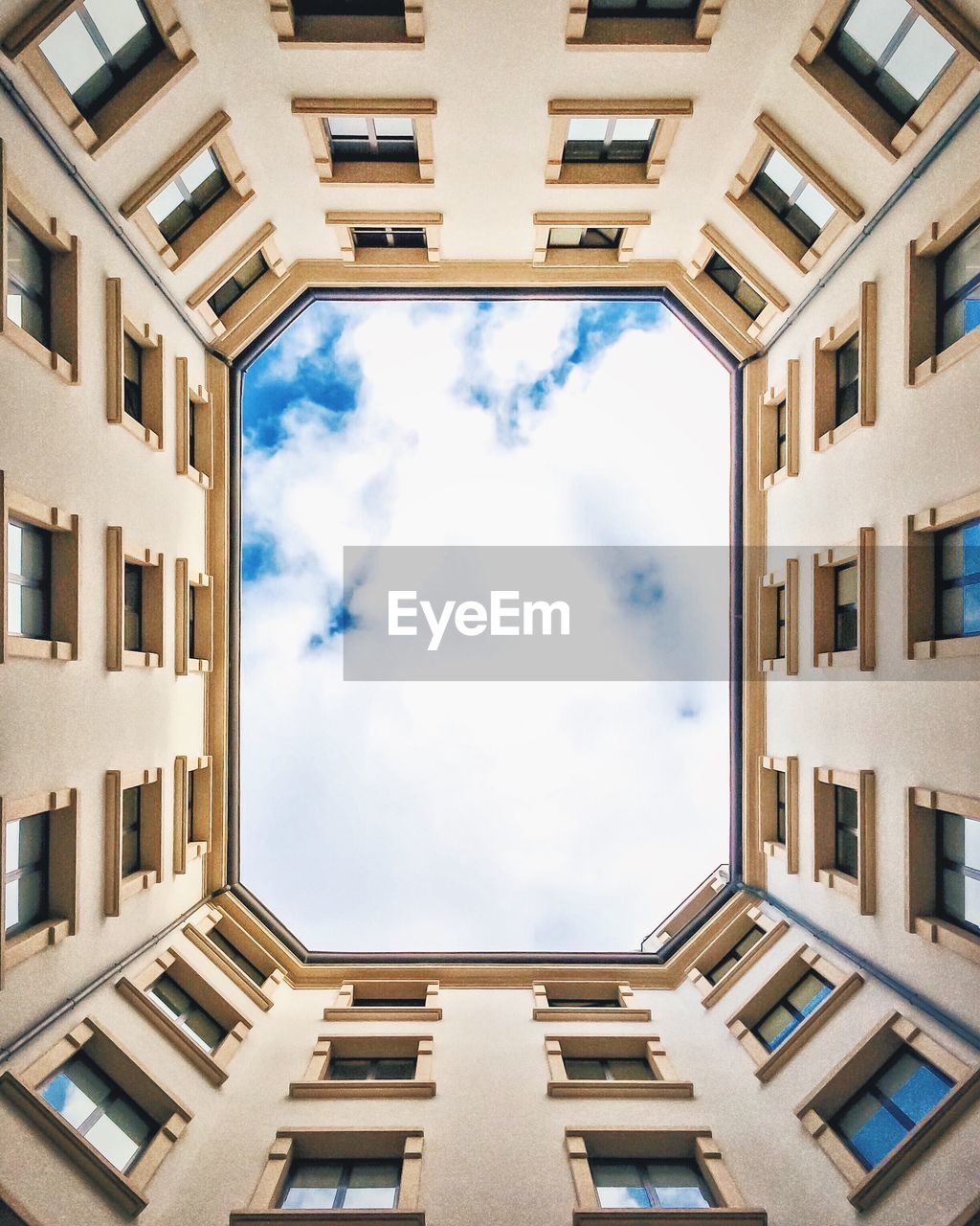 Directly below shot of cloudy sky seen amidst buildings