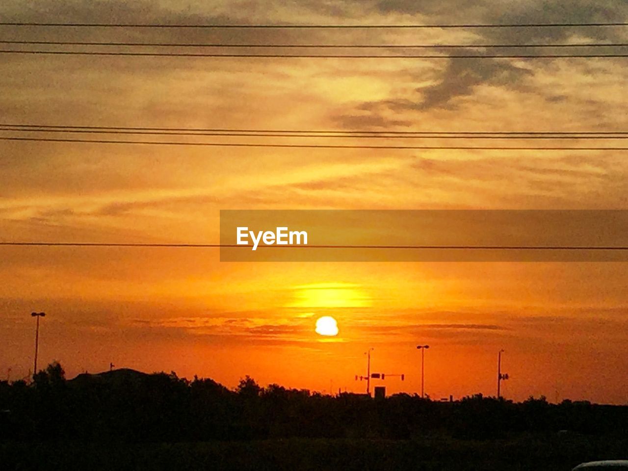 SILHOUETTE OF POWER LINES AGAINST SUNSET SKY