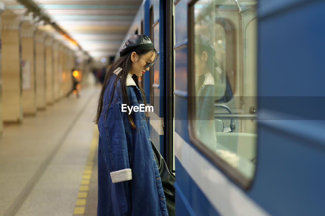 Stylish asian woman enter subway carriage. young japanese fashion model, lifestyle blogger in metro