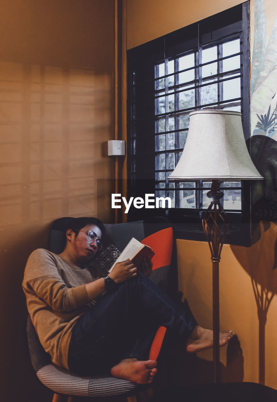 Young man using mobile phone while sitting on sofa at home