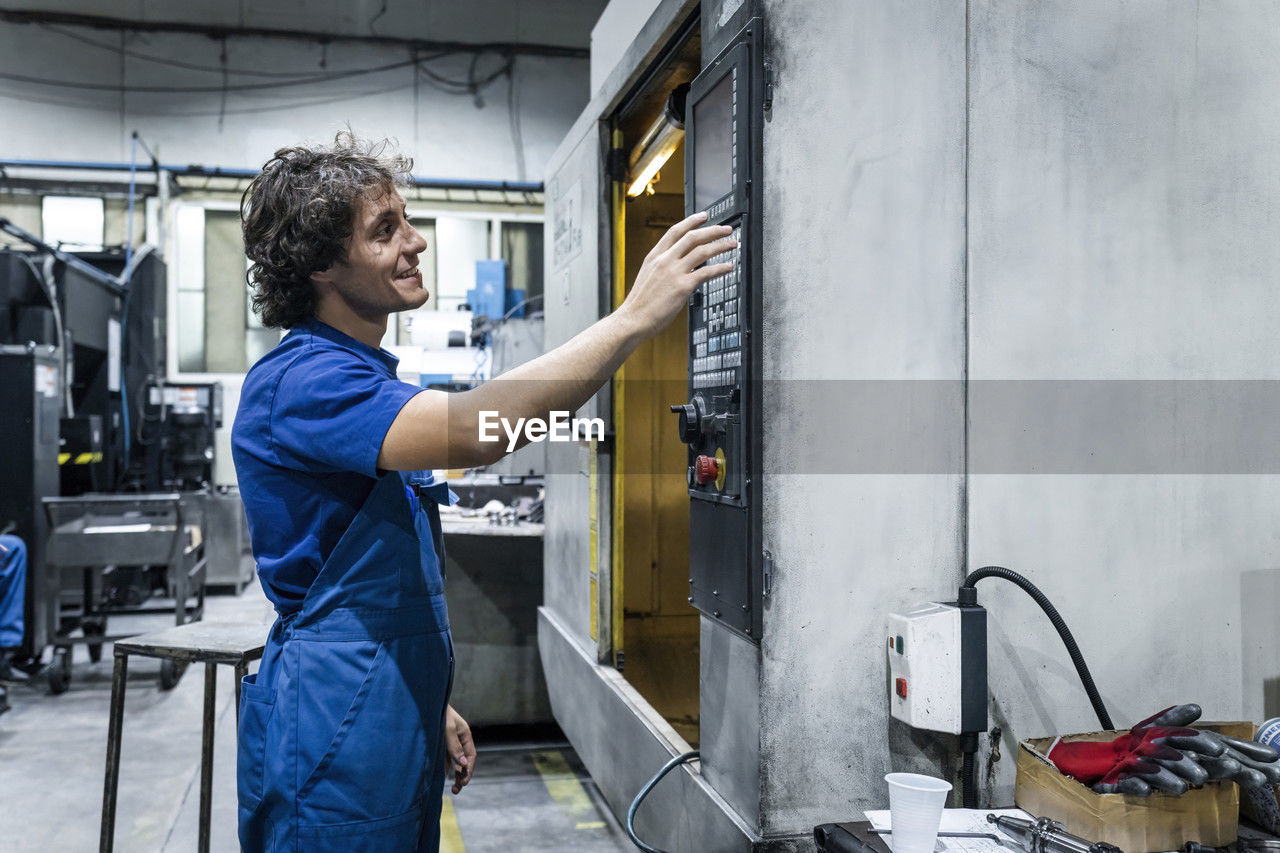 Smiling technician operating cnc machine in metal industry