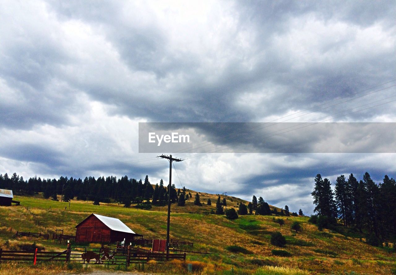 Country house on landscape against clouds