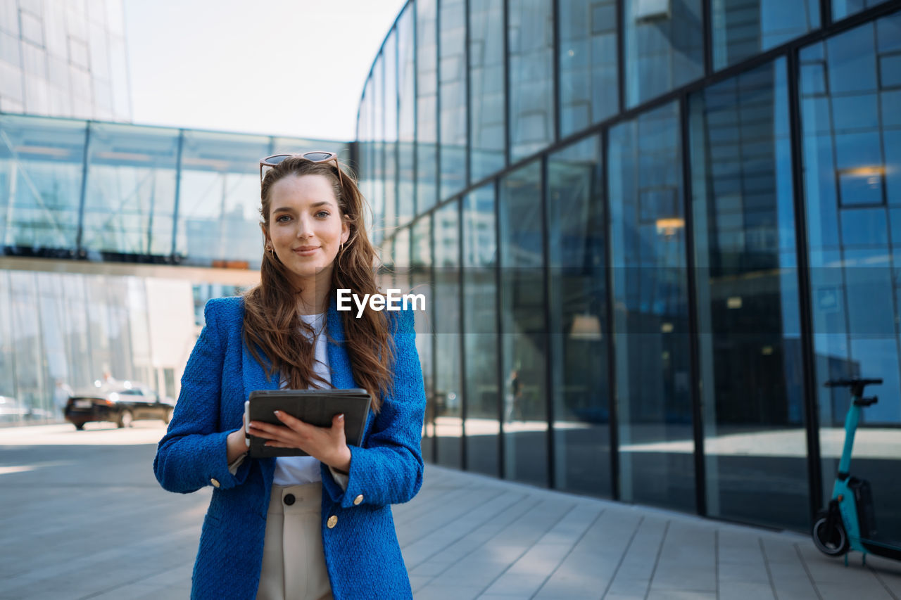 Successful woman real estate agent holding tablet and looking to camera. business centre location.