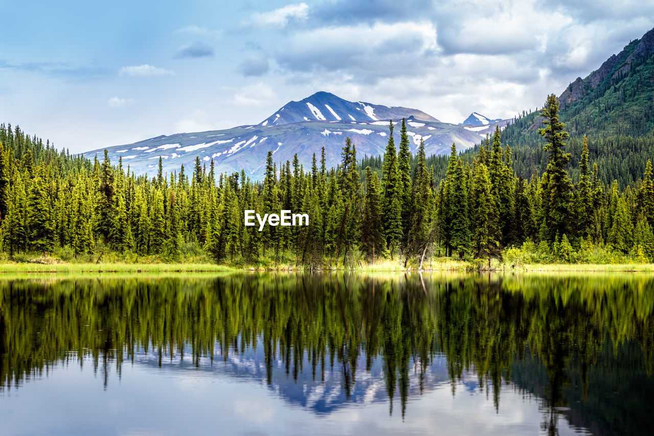 Scenic view of lake by trees against mountain range