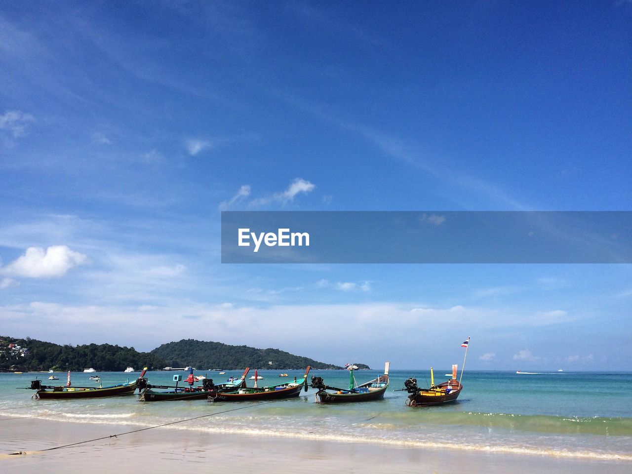 Sailboats moored on sea against blue sky