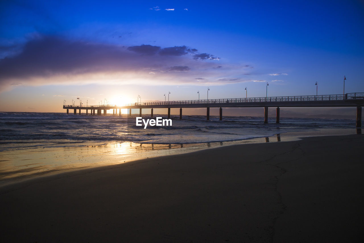 SCENIC VIEW OF BEACH AGAINST SKY DURING SUNSET