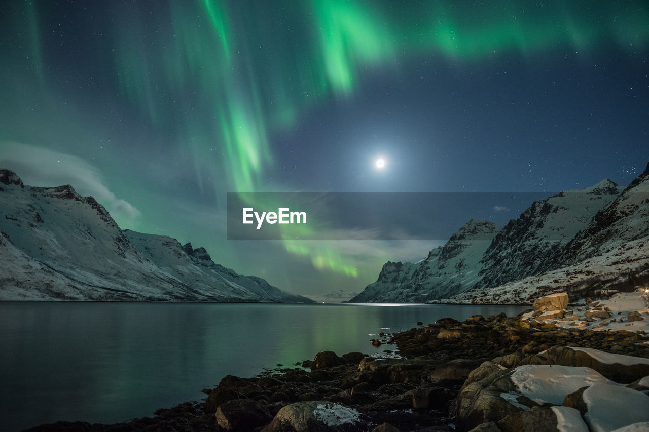 Scenic view of lake and mountains against sky at night