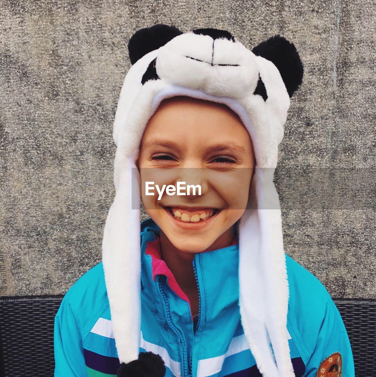 Portrait of smiling boy wearing panda knit hat against wall