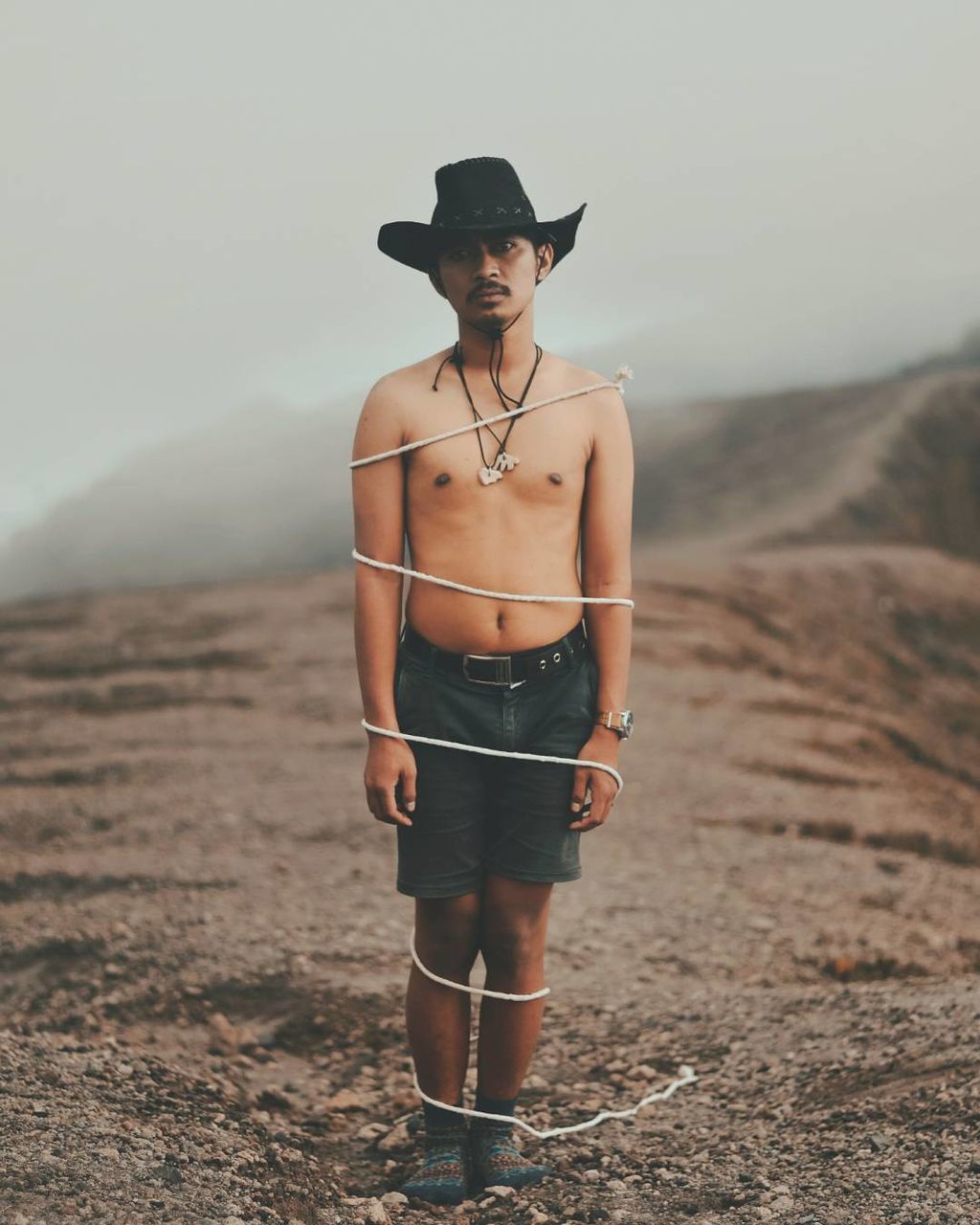 PORTRAIT OF YOUNG MAN WEARING HAT STANDING AGAINST SKY