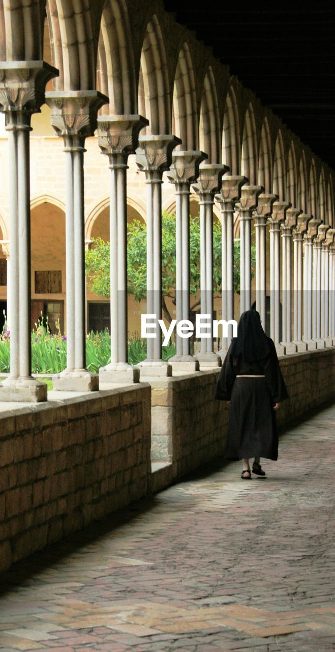 Full length rear view of nun walking in church corridor