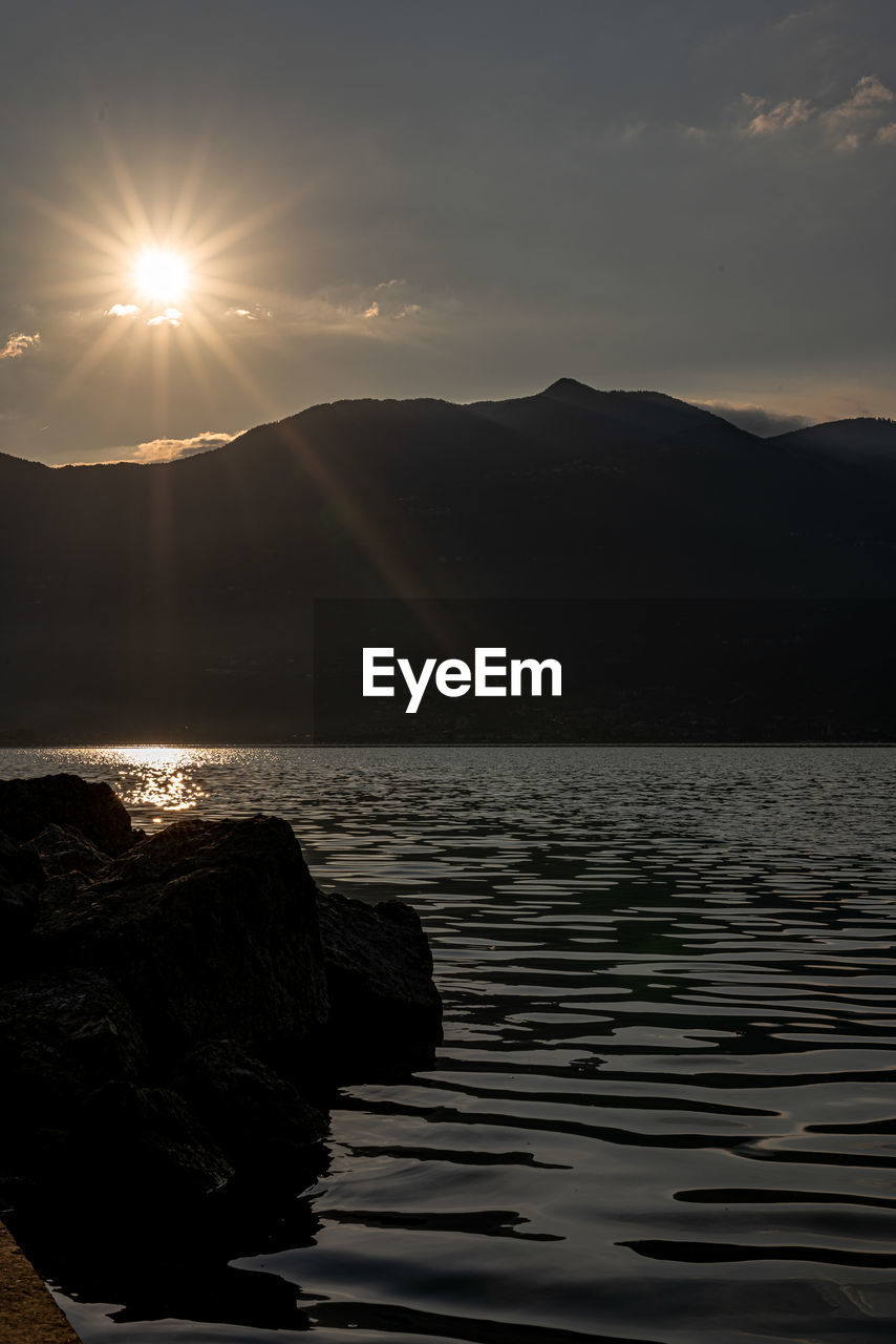 SCENIC VIEW OF SEA BY MOUNTAINS AGAINST SKY DURING SUNSET