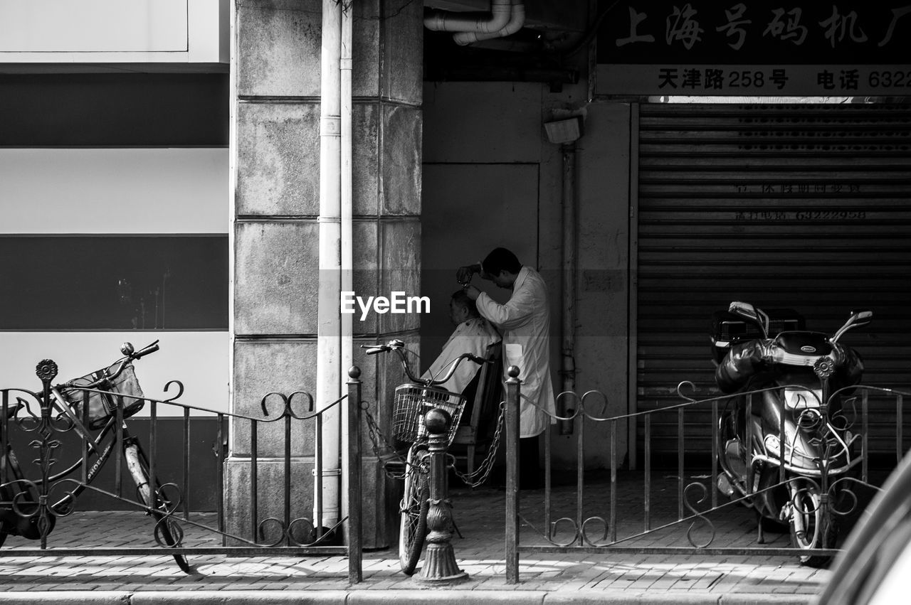 PEOPLE ON BICYCLE OUTSIDE BUILDING