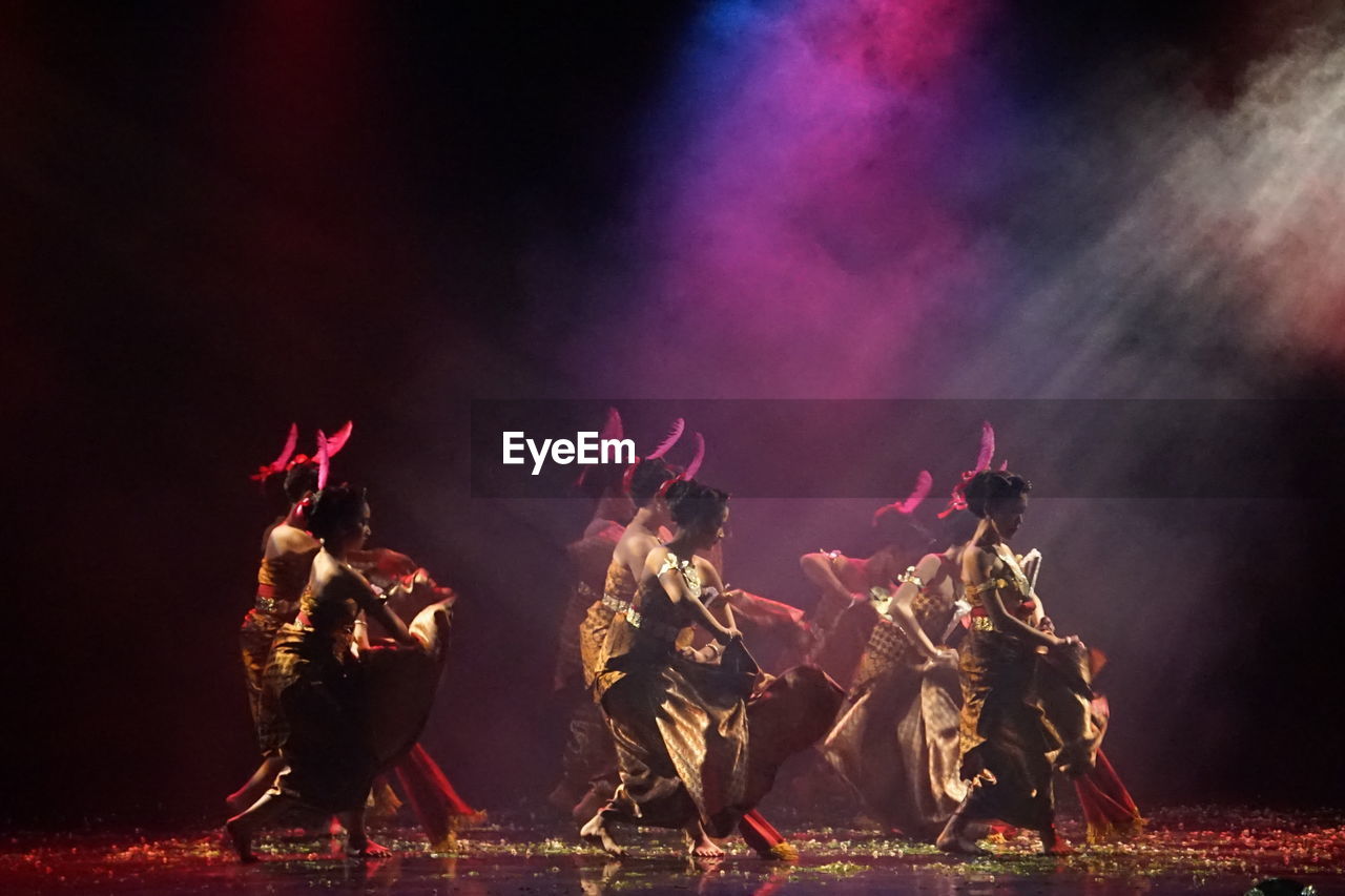 GROUP OF PEOPLE IN ILLUMINATED TRADITIONAL CLOTHING DURING NIGHT