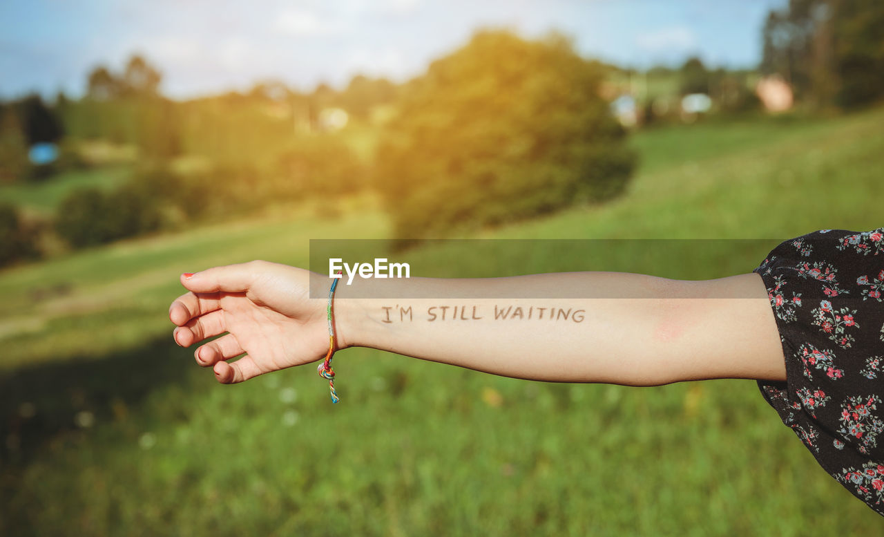 Cropped hand of woman showing text written on forearm at park