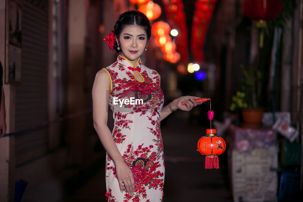 Portrait of young woman wearing cheongsam during festival at night