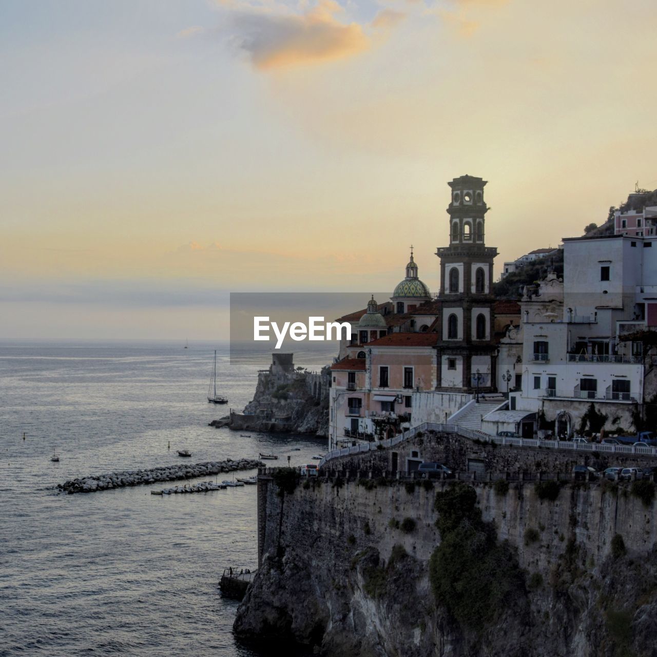 Buildings by sea against sky during sunset