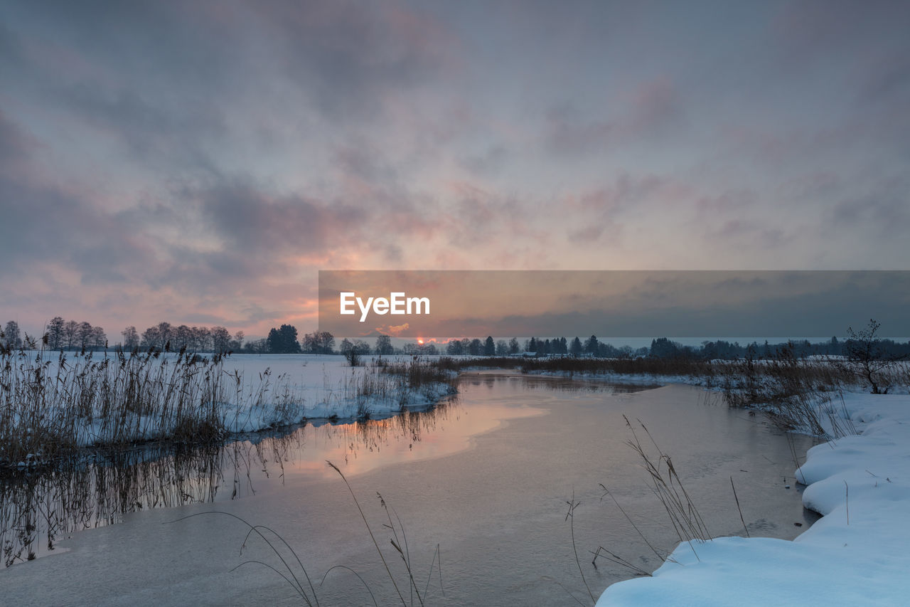 FROZEN LAKE AGAINST SKY DURING SUNSET