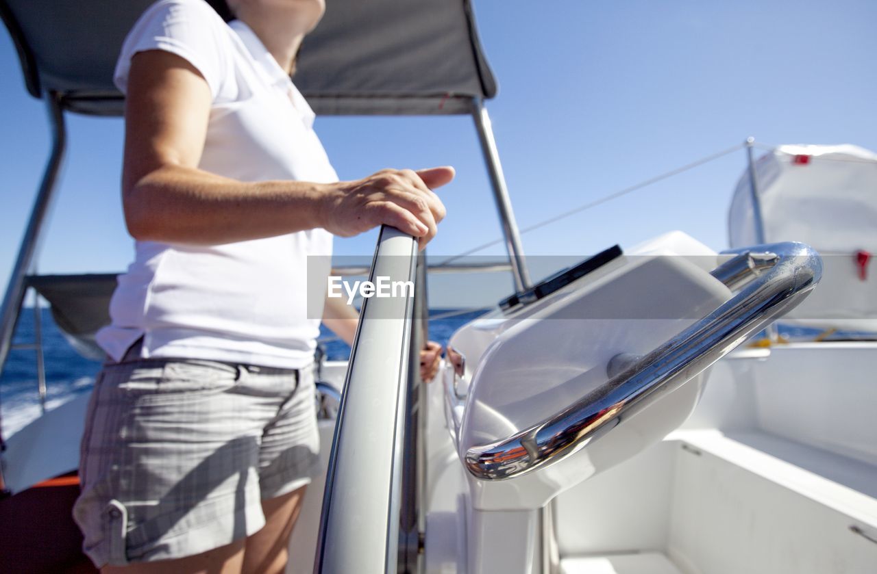 A woman onboard a catamaran enjoy helming by a beautiful sunny day.