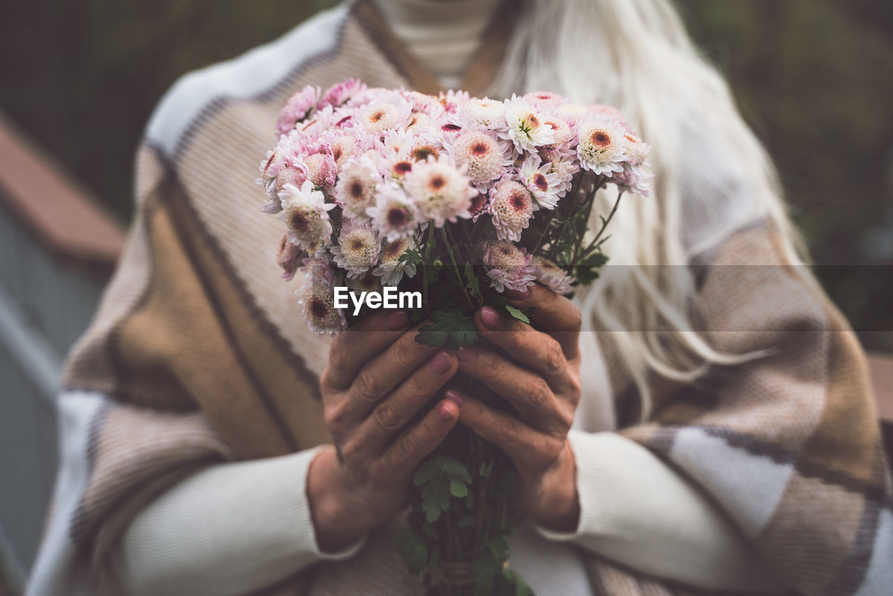 Midsection of senior woman holding flower bouquet