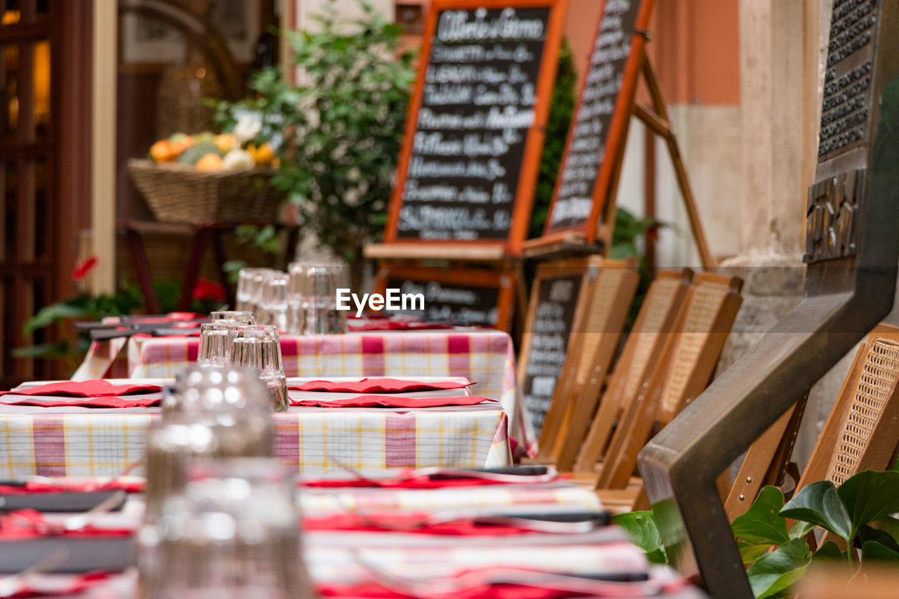 table, selective focus, chair, seat, arrangement, business, no people, furniture, large group of objects, setting, day, place setting, architecture, cafe, absence, empty, in a row, text, restaurant, built structure, glass, outdoors, order