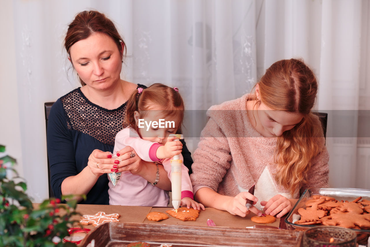 Mother and daughters preparing gingerbread cookies at home