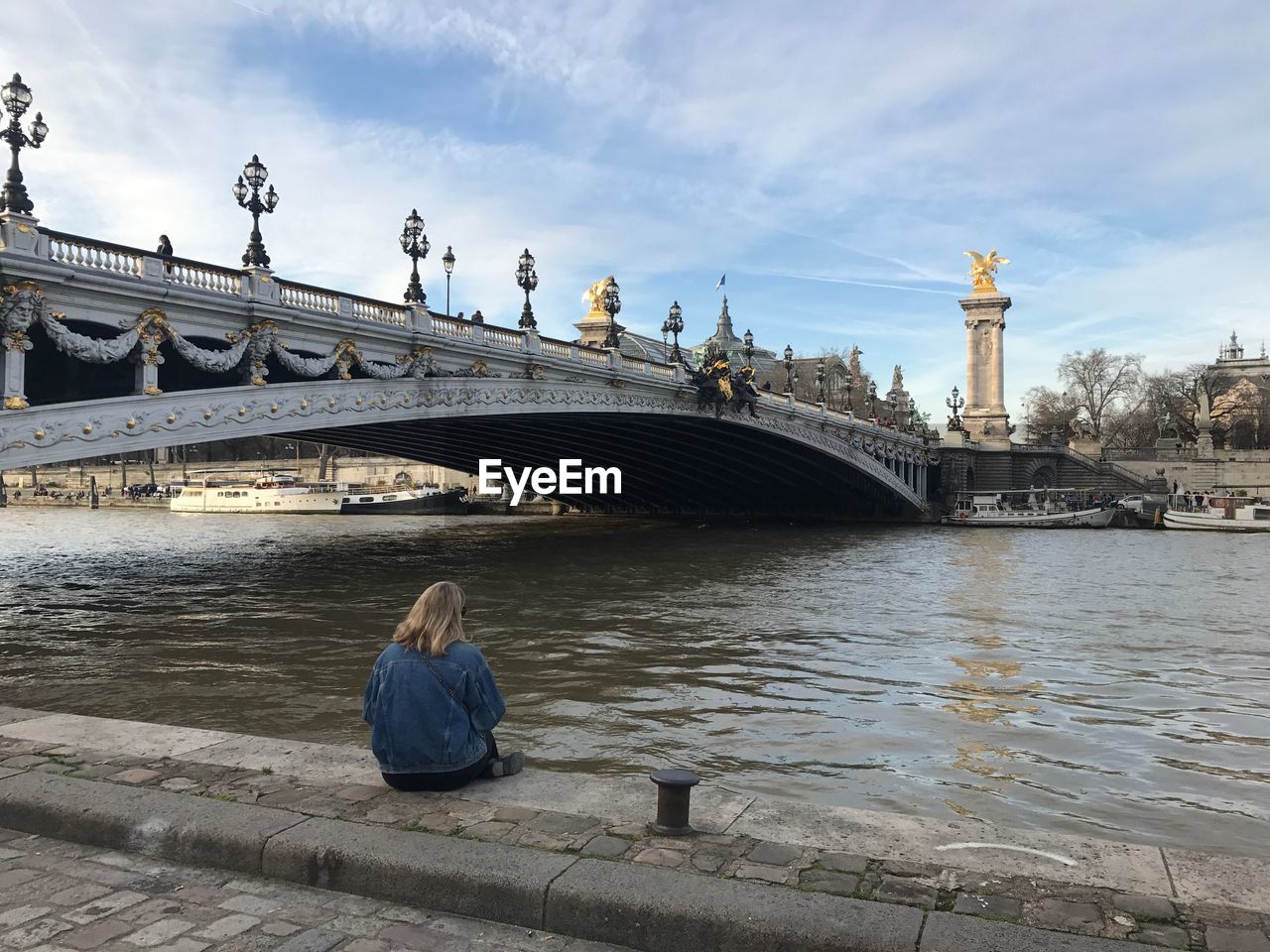 REFLECTION OF WOMAN ON BRIDGE OVER WATER AGAINST SKY