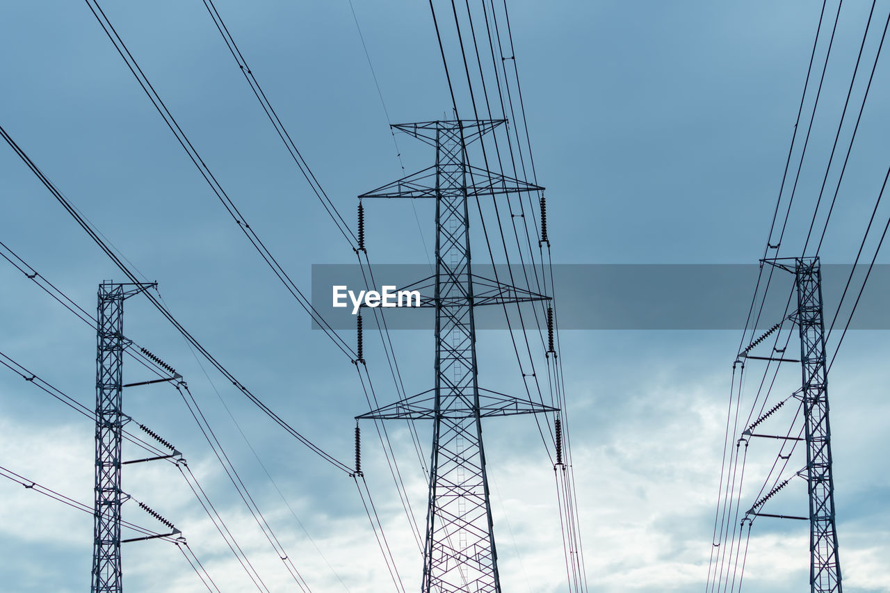 High voltage electric pylon and electrical wire against blue sky and clouds. 