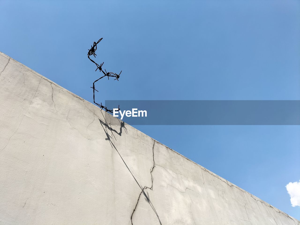 Barbed wire over a high fence against the sky