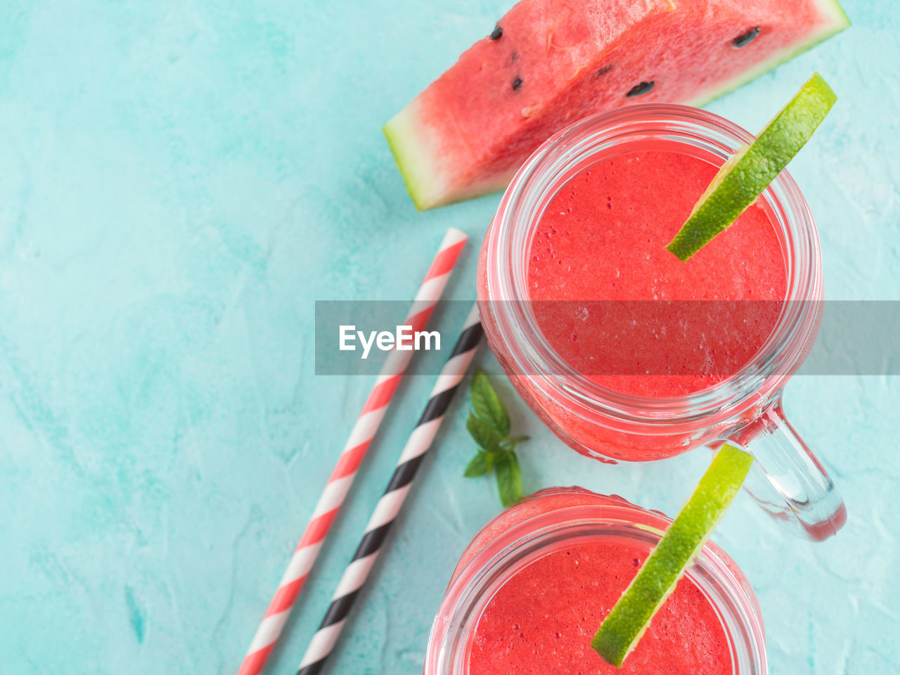 Watermelon smoothie with lime and mint in mason jar on white wooden background
