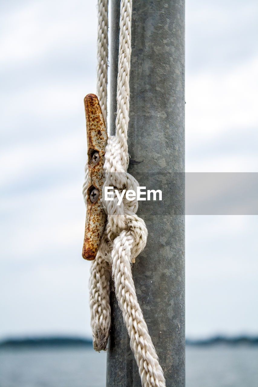 CLOSE-UP OF ROPE TIED TO WOODEN POST