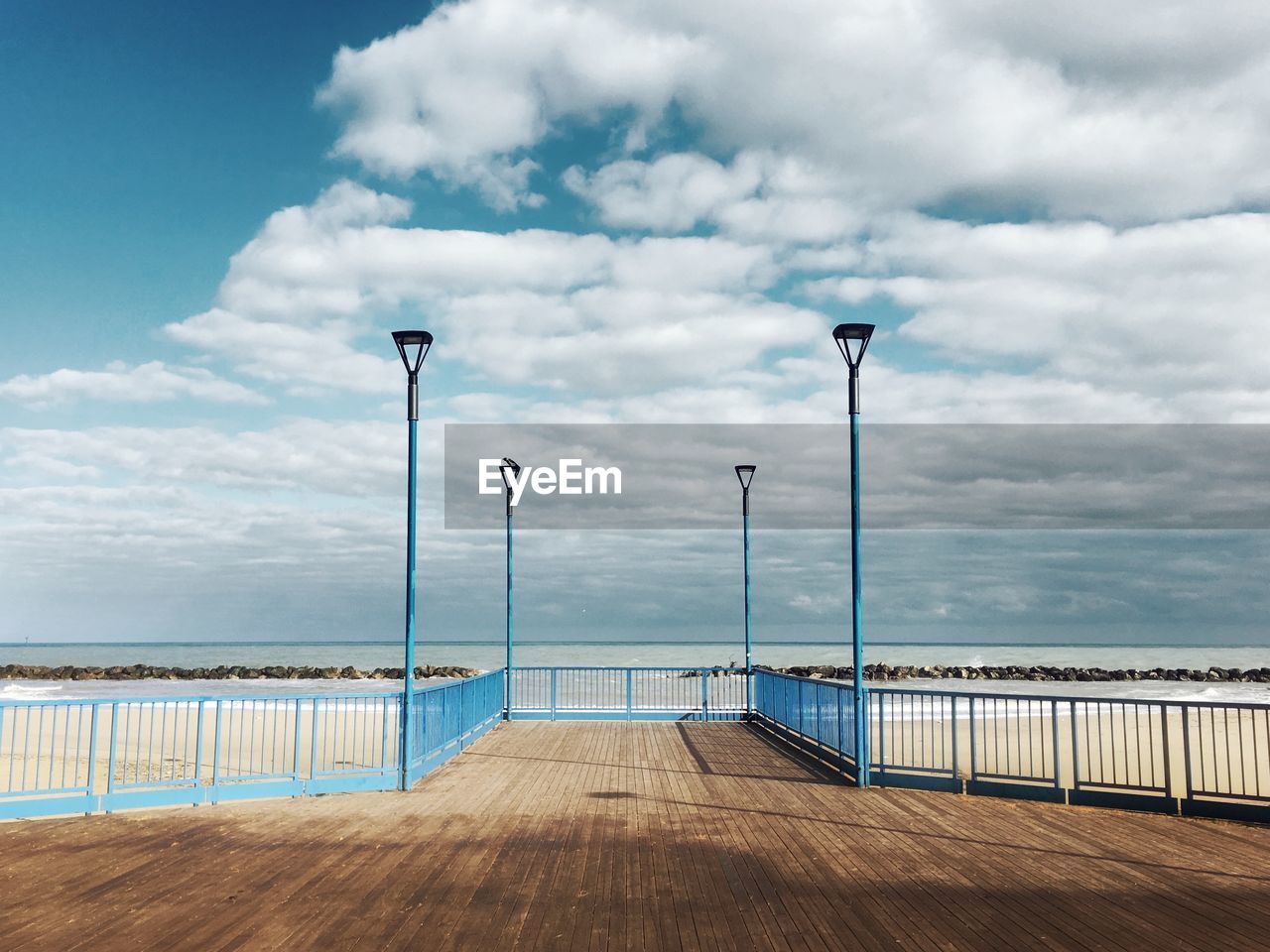 Empty pier by sea against sky