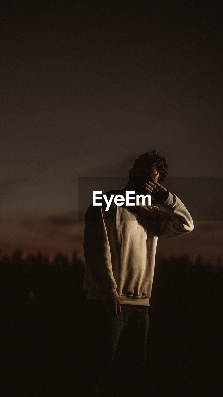 Young man looking away against sky at night