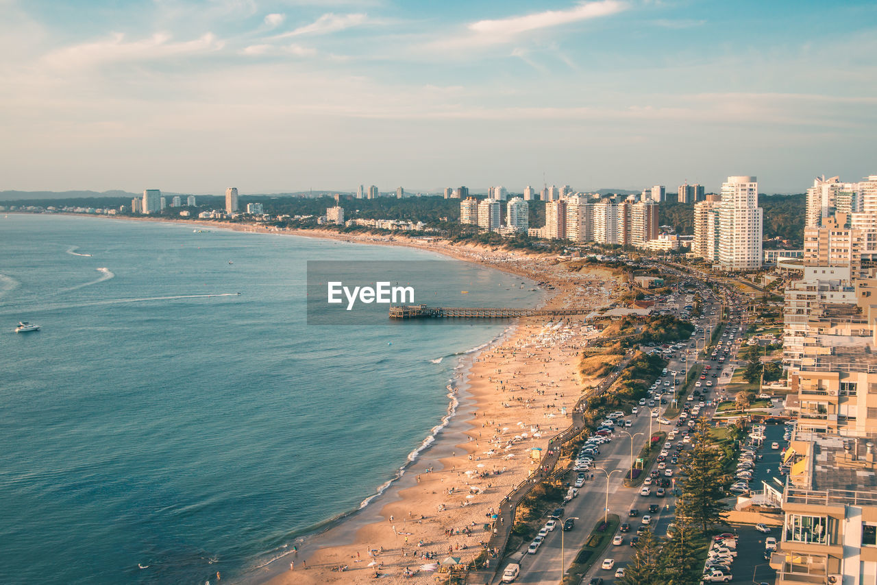 Aerial view of city by sea against sky