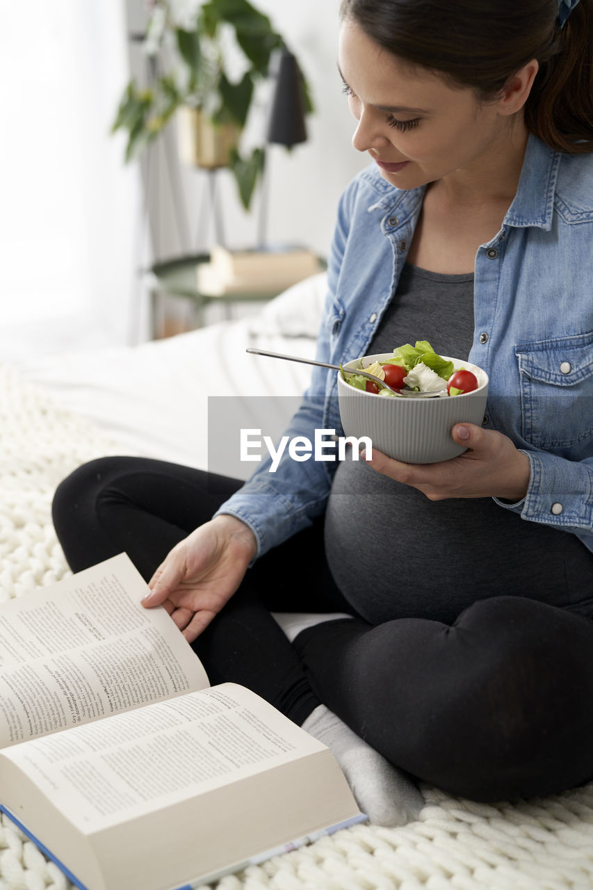 Pregnant woman eating salad at home