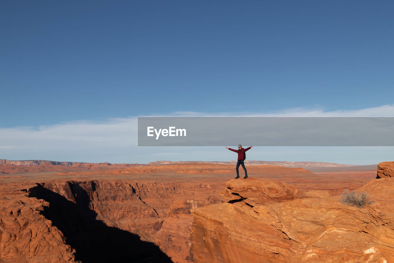 Young man opening arms in the form of freedom at horseshoe bend in the grand canyon, arizona, usa