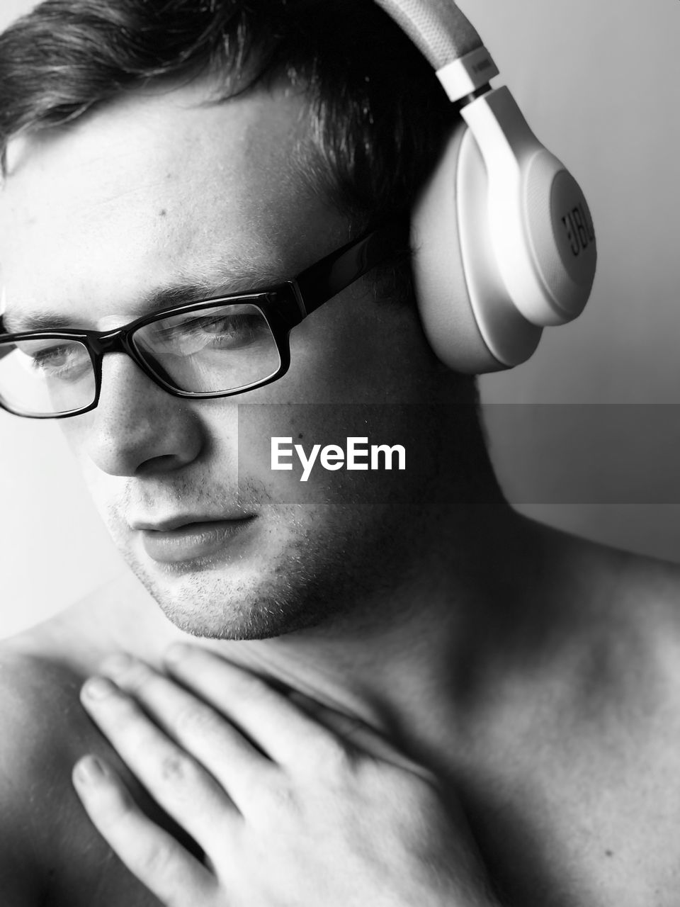 Close-up of shirtless young man listening to music through headphones