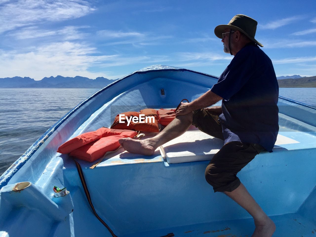 Side view of men on boat in sea against sky