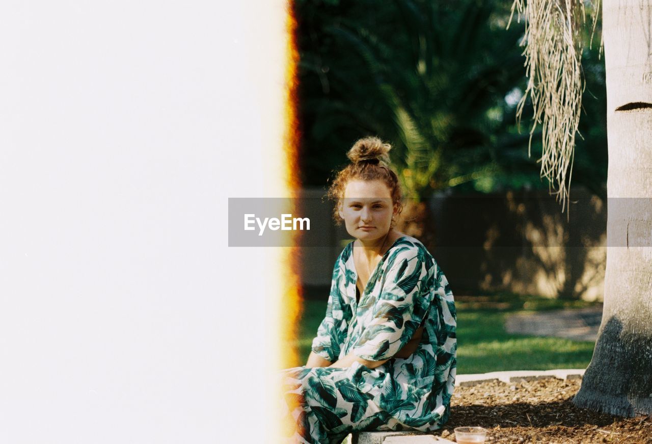 PORTRAIT OF A SMILING GIRL STANDING AGAINST TREES