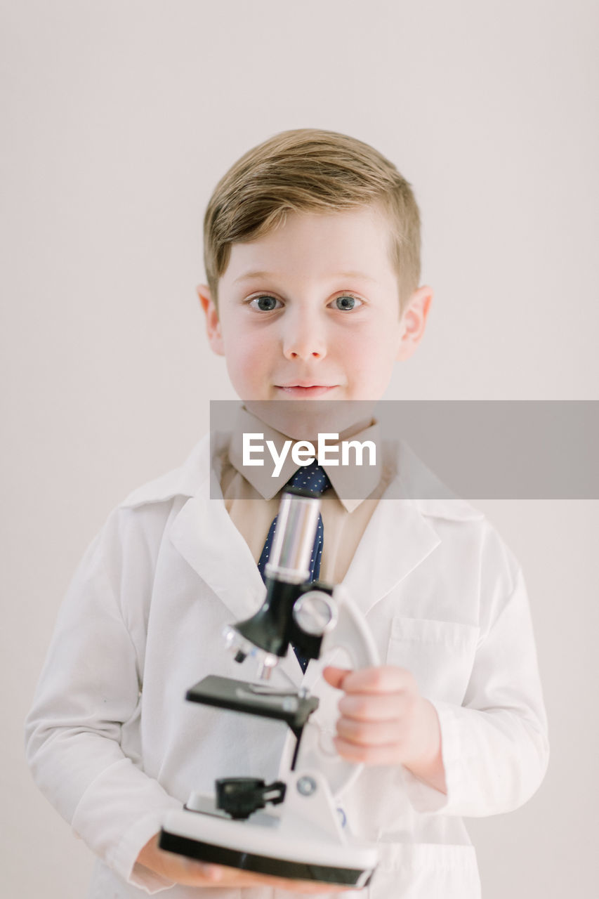 Young child holding a microscope smiling at camera