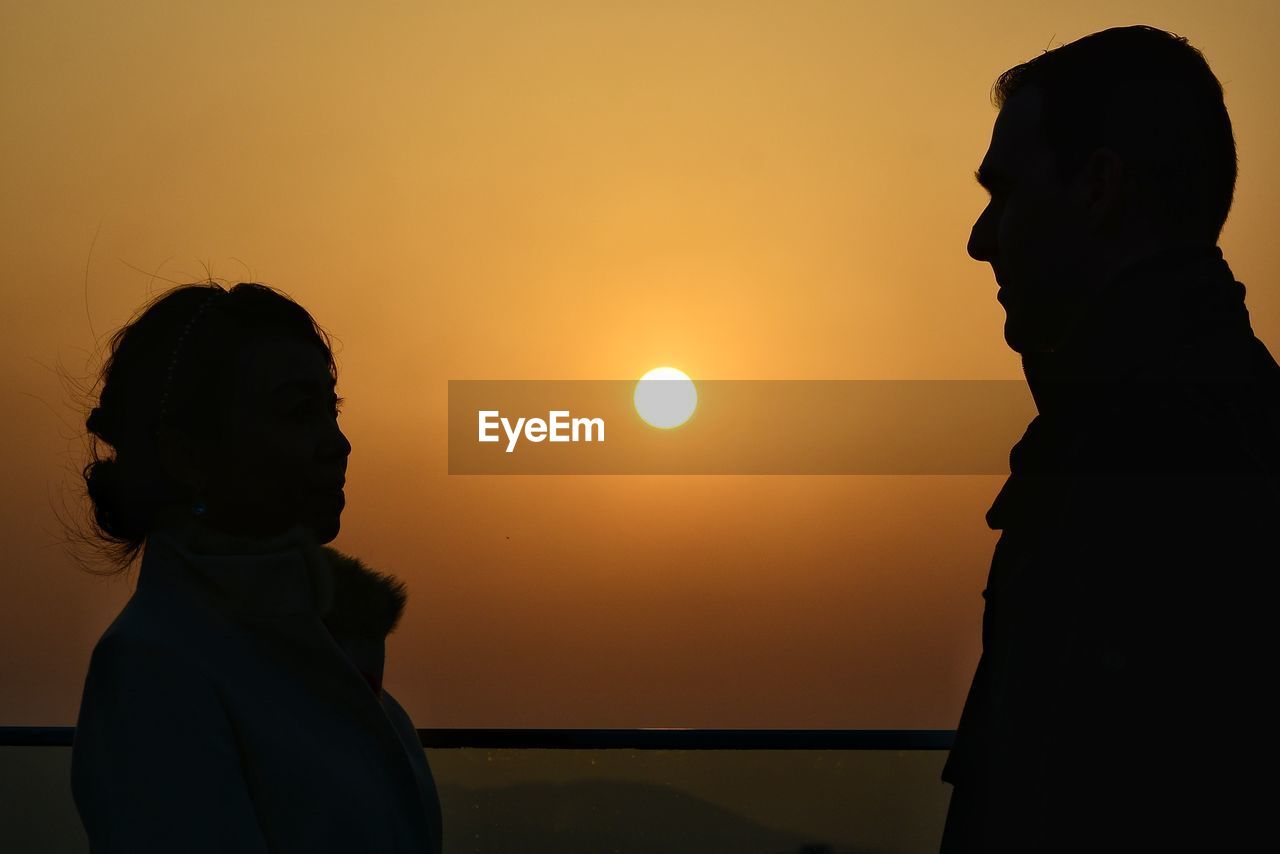 SILHOUETTE WOMAN STANDING AGAINST SEA DURING SUNSET