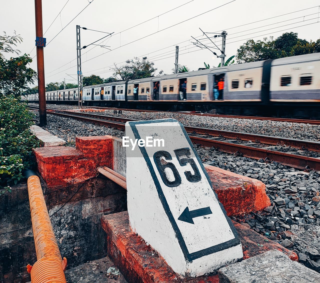 railroad track, rail transportation, track, transportation, transport, urban area, communication, sign, train, mode of transportation, day, railway, vehicle, no people, architecture, nature, sky, electricity, text, tree, cable, art, outdoors, public transportation, city, lane, road sign, road, railroad station platform, built structure, power line, western script