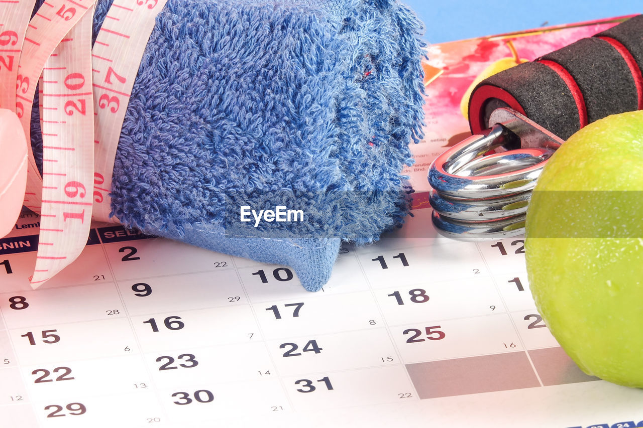 High angle view of towel with apple and tape measure on calendar
