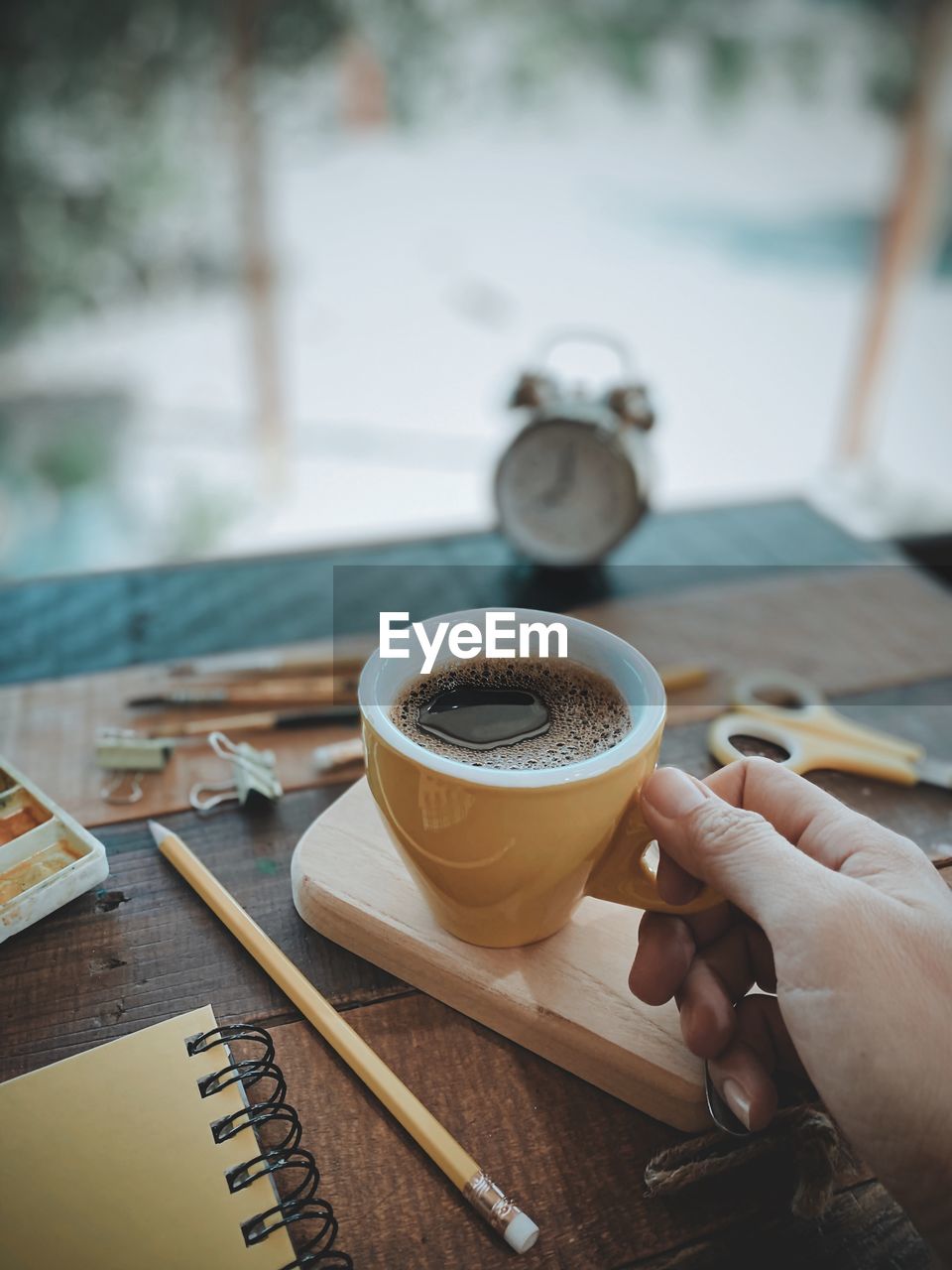 Cropped image of hand holding coffee cup on table