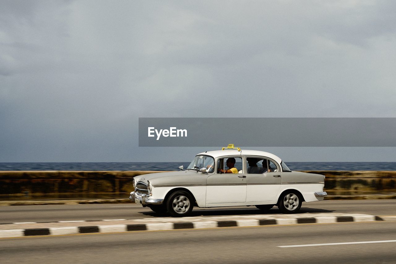 VINTAGE CAR ON ROAD AGAINST SEA