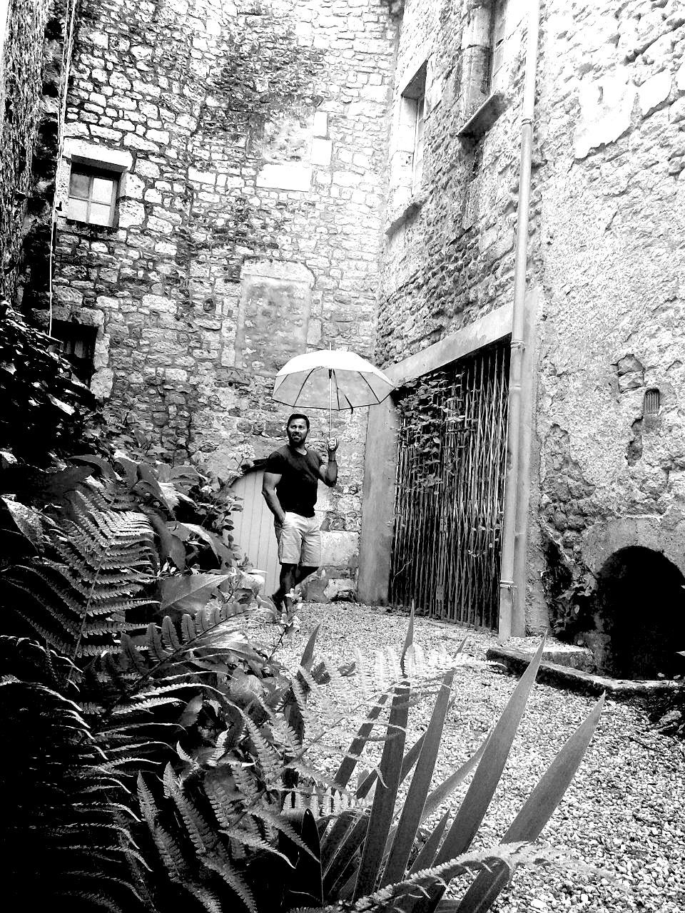 Man with umbrella standing in narrow alley