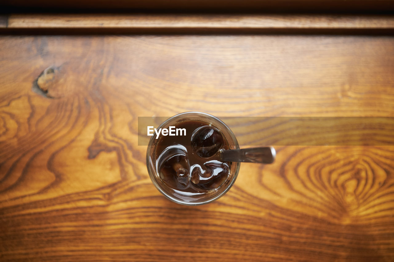 Close-up of glass of vietnamese iced coffee on wooden table. selective focus on ice cubes. 